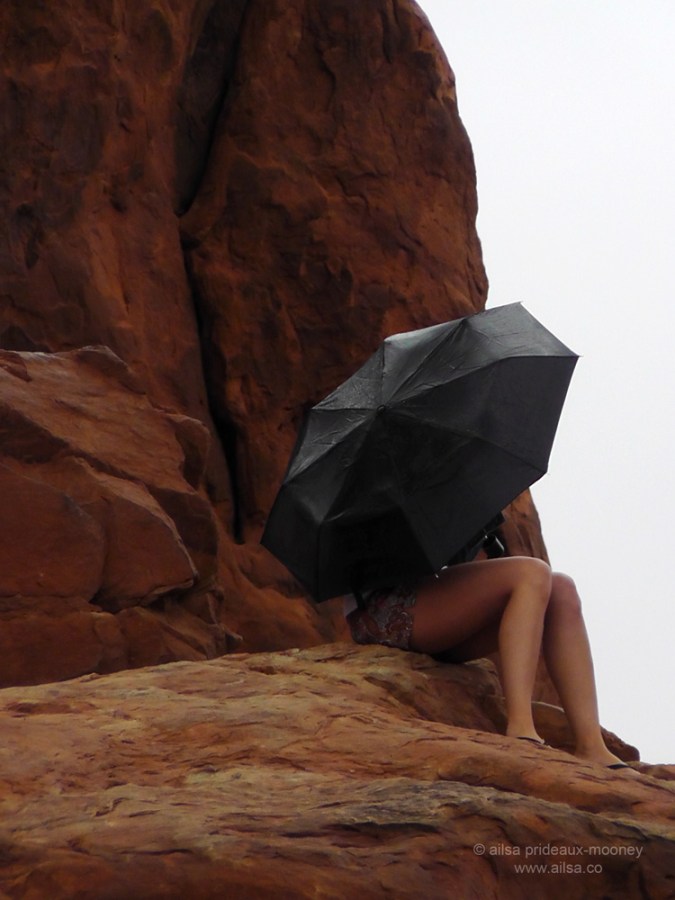 foggy arches national park girl umbrella monsoon season utah sitting seated